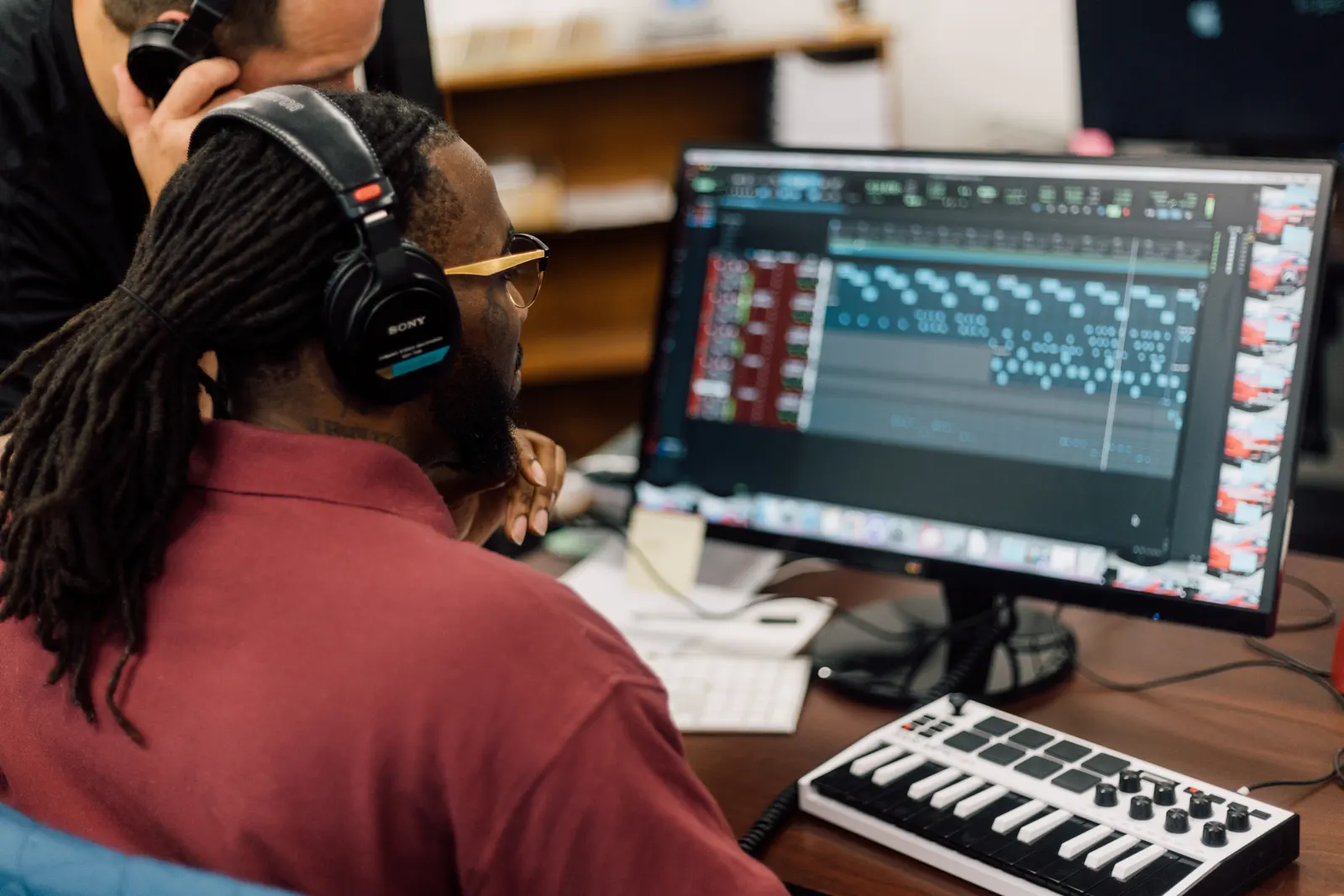 A student producing audio at a workstation with studio headphones